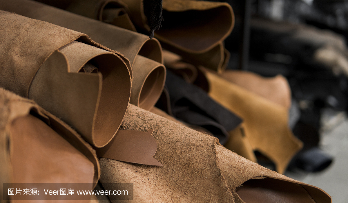 不同的皮革卷在一起。彩色皮革的碎片。天然棕红色皮革卷。生产箱包、鞋、服装及配件的原材料。